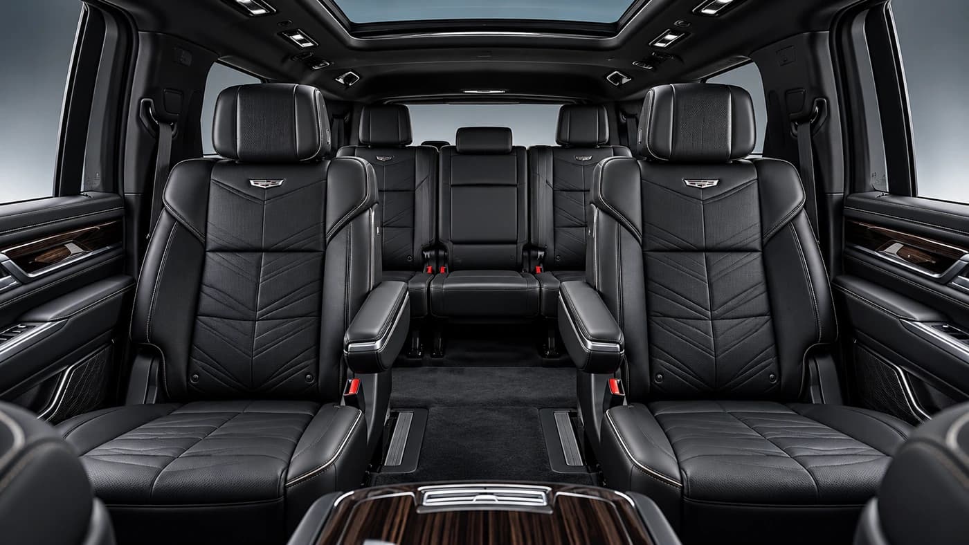 Cadillac Escalade interior from the rear: diamond-stitched black leather seats, wood trim and overhead lighting.