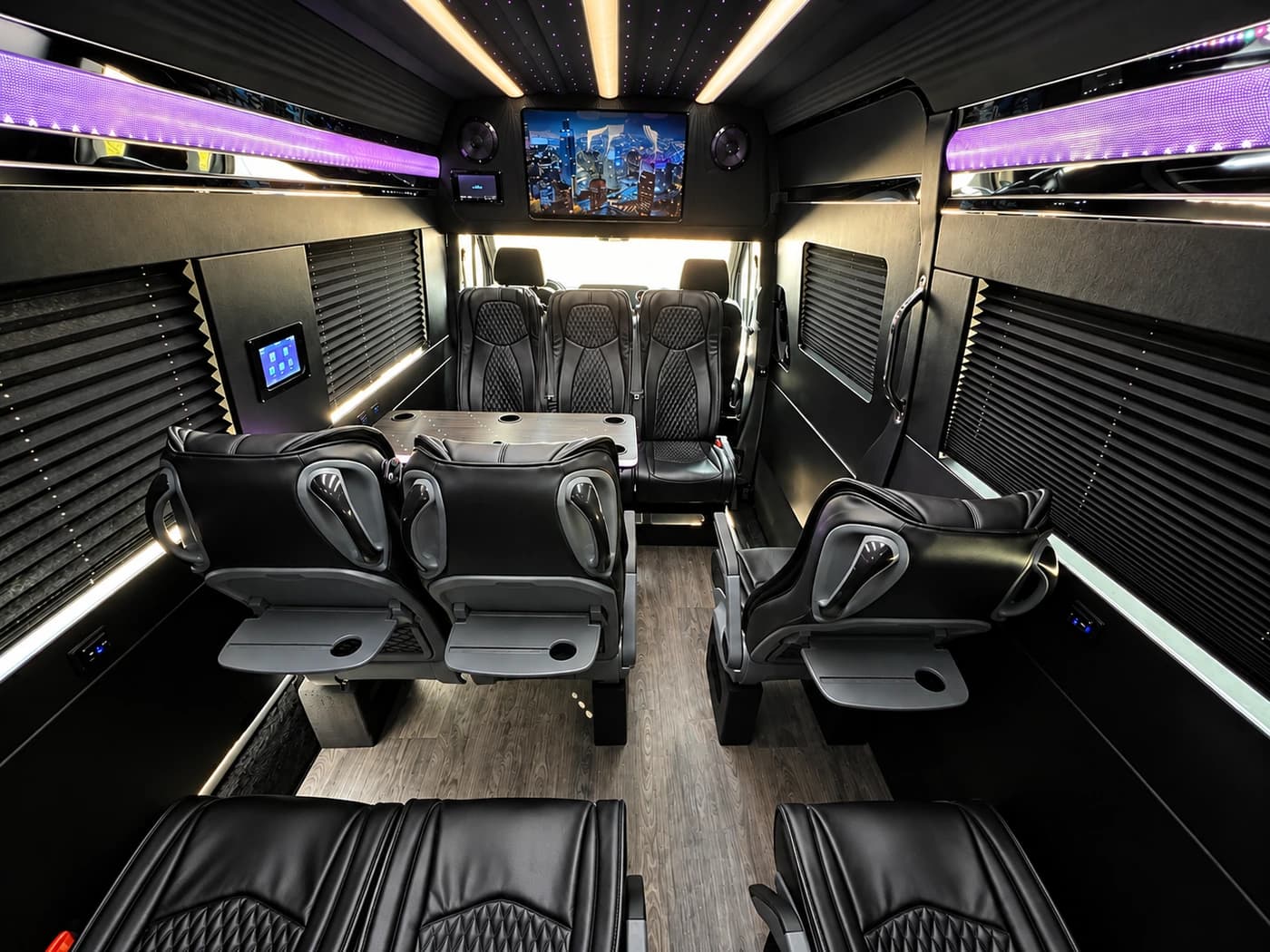 Mercedes-Benz Executive Sprinter cabin with black leather seats and a large TV screen.