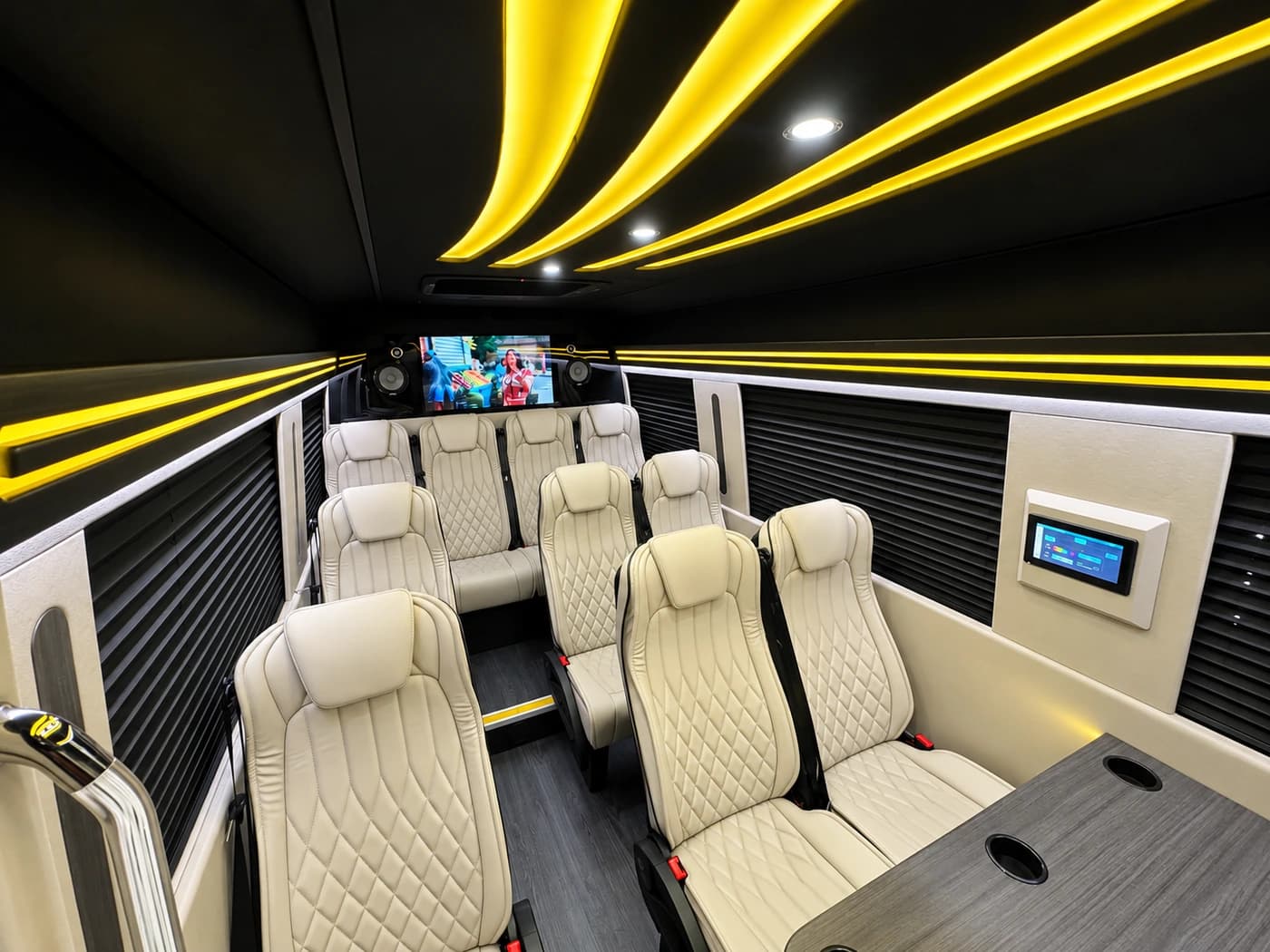 Mercedes-Benz Executive Sprinter cabin with cream leather seats, yellow LED lighting and a rear TV screen.