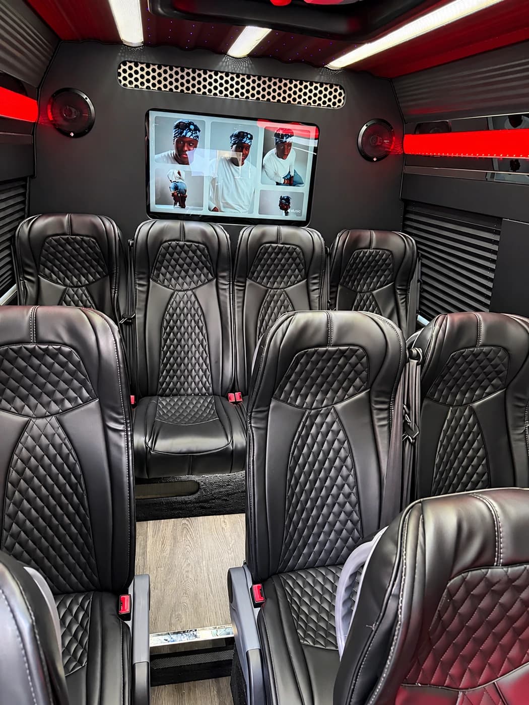 Mercedes-Benz Executive Sprinter cabin with quilted black leather seats, a rear screen, red lighting and wood floor.