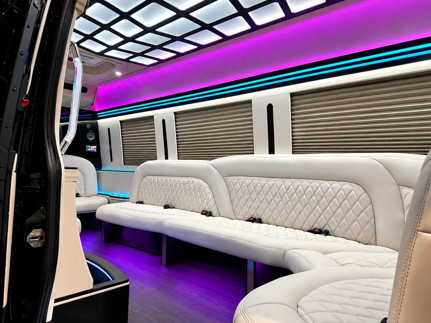 Mercedes-Benz Party Limo Sprinter with white leather seats, purple LED lighting, wood floor and a side bar counter.